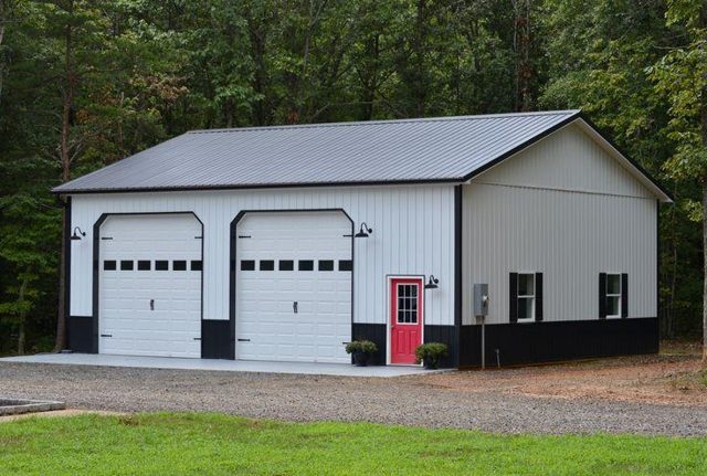 A two-bay garage with a dark metal roof, white metal siding and black wainscot
